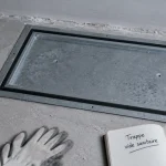 Trappe acces vide sanitaire rectangulaire sur dalle béton, joint et cadre métalliques visibles